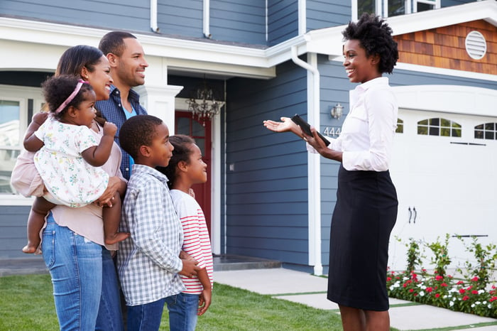 Family talking to a real estate agent in front of a home