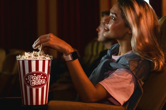 A woman in a movie theater eating popcorn.