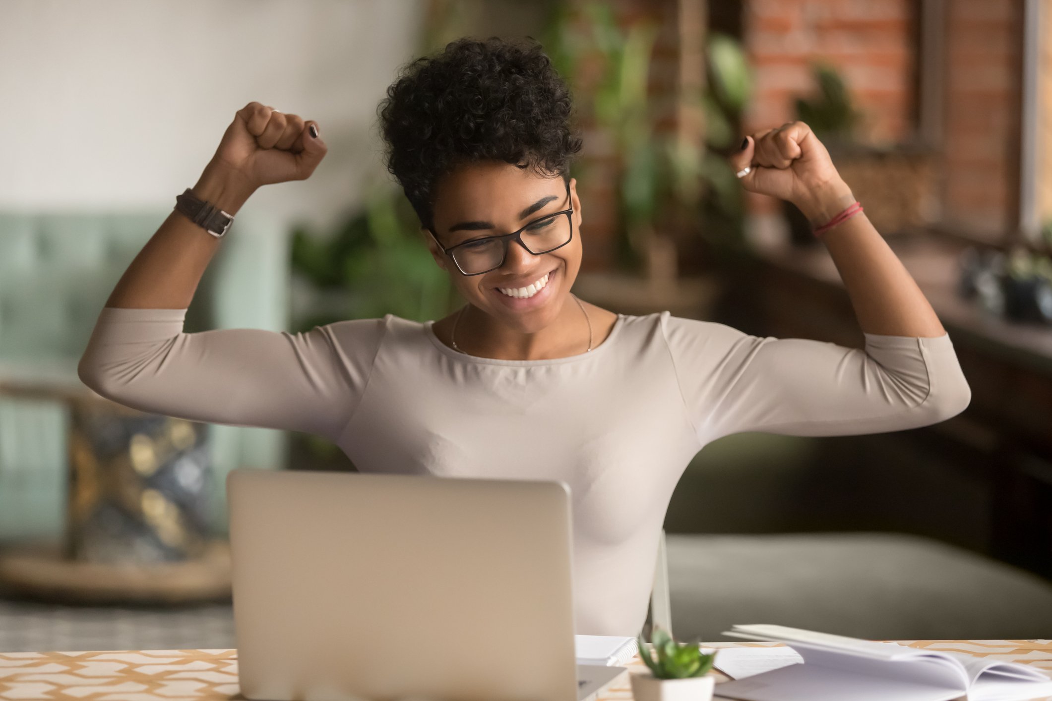 20_05_26 A woman raising her arms in triumph in front of a computer _GettyImages-1144287268