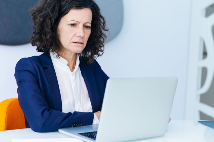 Middle-aged person at a laptop with concerned expression