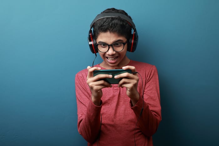 A teenage boy plays a mobile game on his phone.