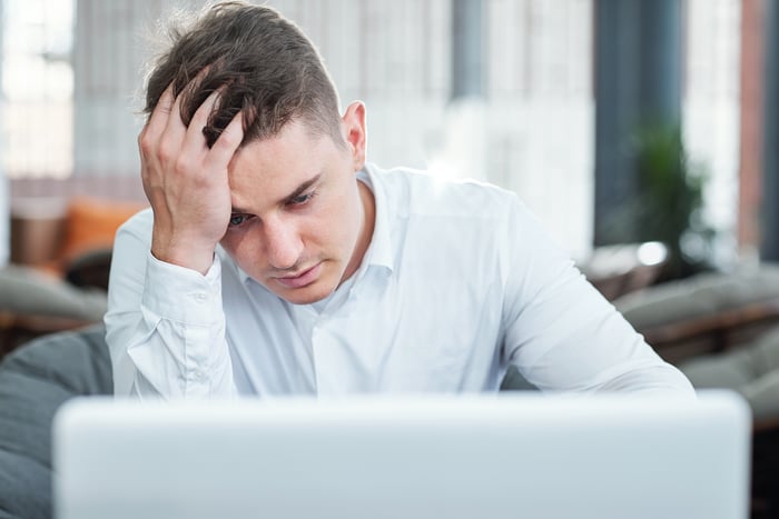 Man at laptop holding his head