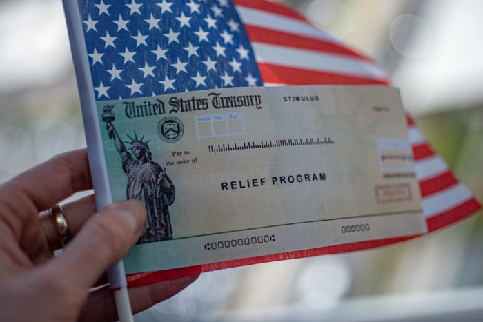 A check labeled Relief Program being held on top of an American Flag.