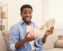 Man with cash and a piggy bank -- GettyImages-1127342239