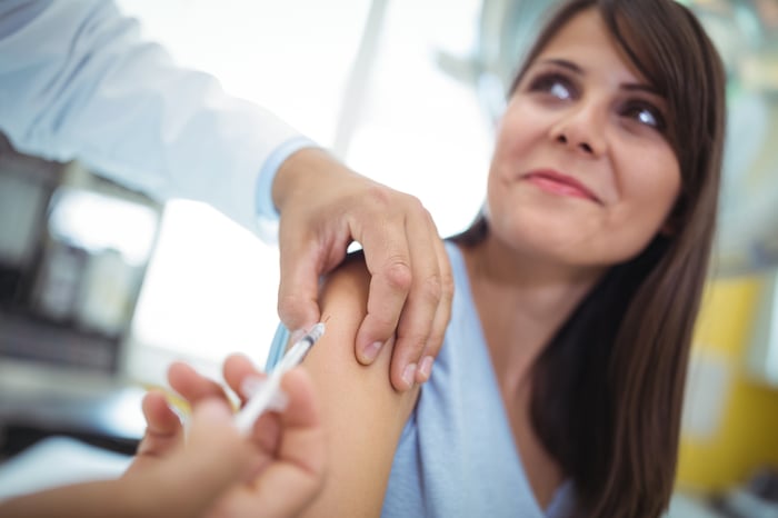 A physician administering a vaccine to a young woman.