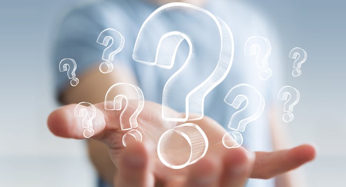 An open hand holding drawings of question marks.