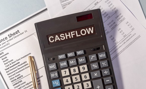 Calculator that reads cashflow, and a pen laying on top of financial statements.