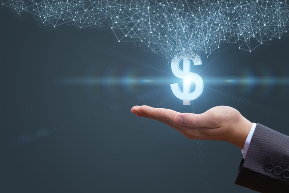 Image of a lighted dollar sign with a grid of connected nodes over a man's outstretched palm