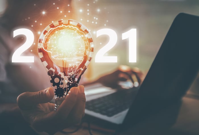 Person working at computer and holding lightbulb that says 2021
