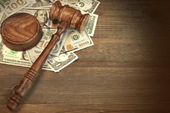 A judge's gavel lies atop a pile of $100 bills.