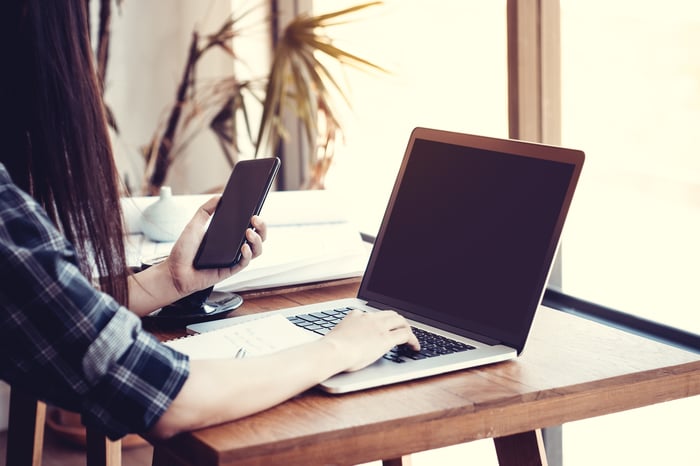 Woman using laptop and smartphone at the same time