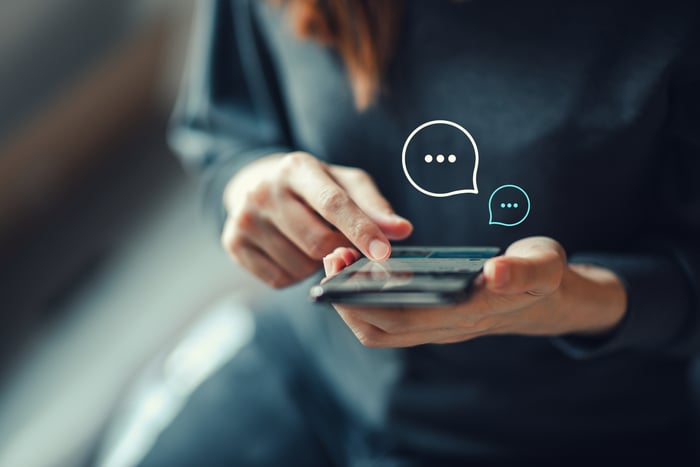 A person using a smart phone with thought bubbles above the phone