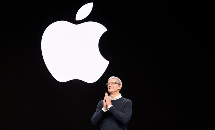 Tim Cook presenting onstage with large Apple logo behind him