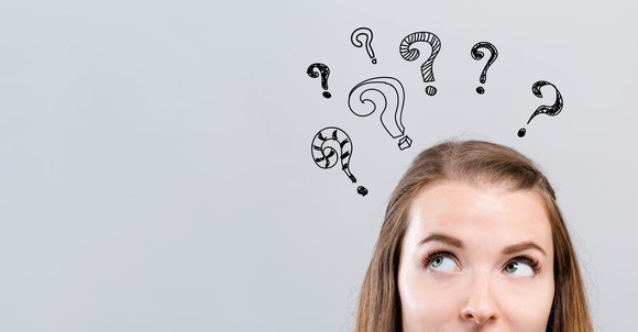Woman looking up at question marks hovering above her head.