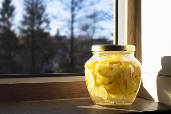 A jar of lemonade next to a window.