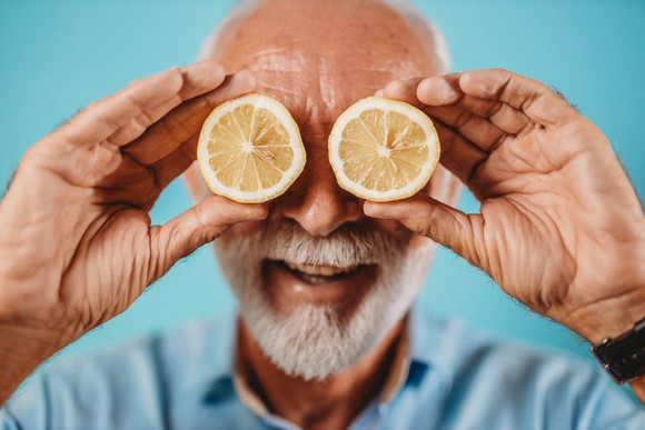 Man holding cut lemons over his eyes and smiling.