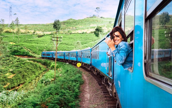 A woman looks out a train window at green countryside.