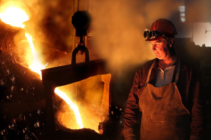 A man standing in front of steel being poured.