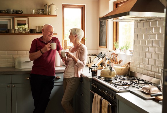 Senior couple standing in the kitchen drinking coffee