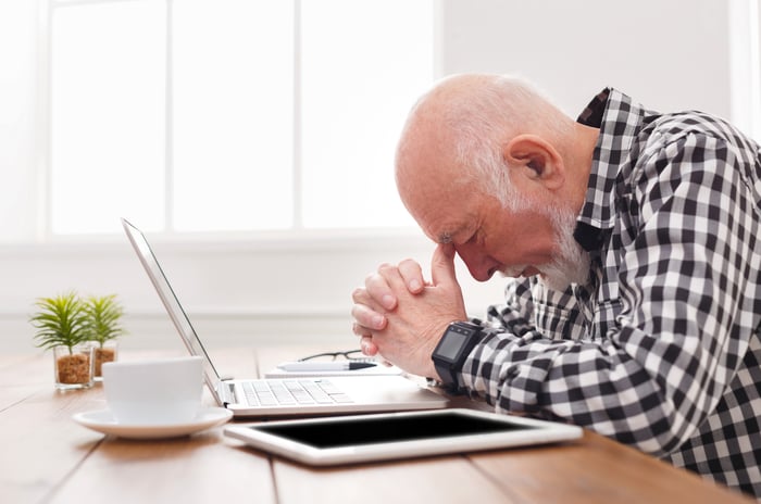 Older man at laptop lowering his head