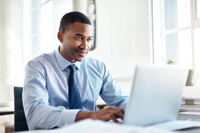 Man in dress shirt and tie typing on laptop