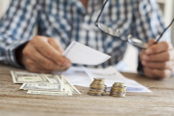 Man at table with dollar bills and coins in front of him