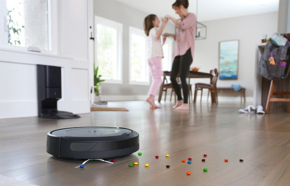 A Roomba cleans up candy as a mother dances with her daughter.
