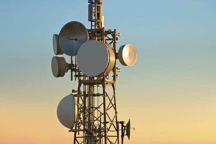 A cellular tower with multiple attached satellite dishes. 