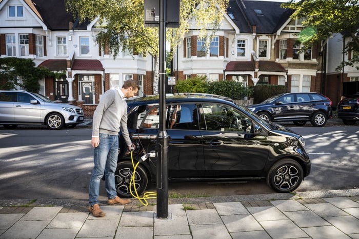 Man charging his car at a light post