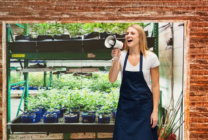 A cannabis farmer speaks into a megaphone while standing in front of her crops.