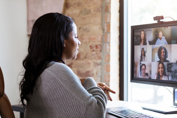 A woman video calling with workers on a computer.