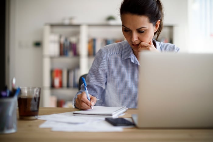 Young woman sitting at a desk writing in a notebook
