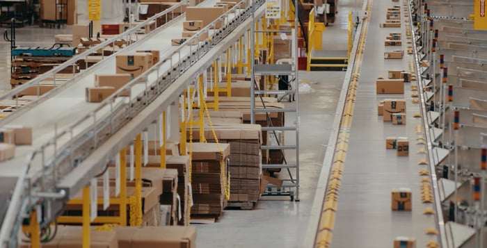 Packages traveling on conveyor belts in an Amazon fulfillment center.