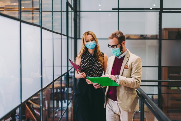 Masked man and  woman in an office looking at documents
