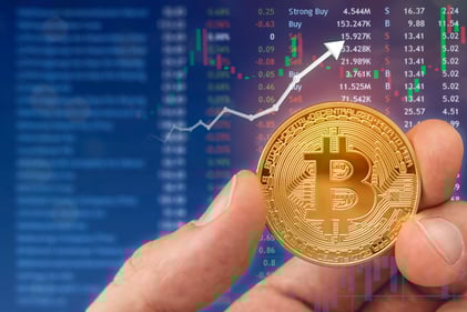 Holding a bitcoin digital currency with laptop in background