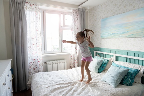 Happy little girl bouncing on a mattress