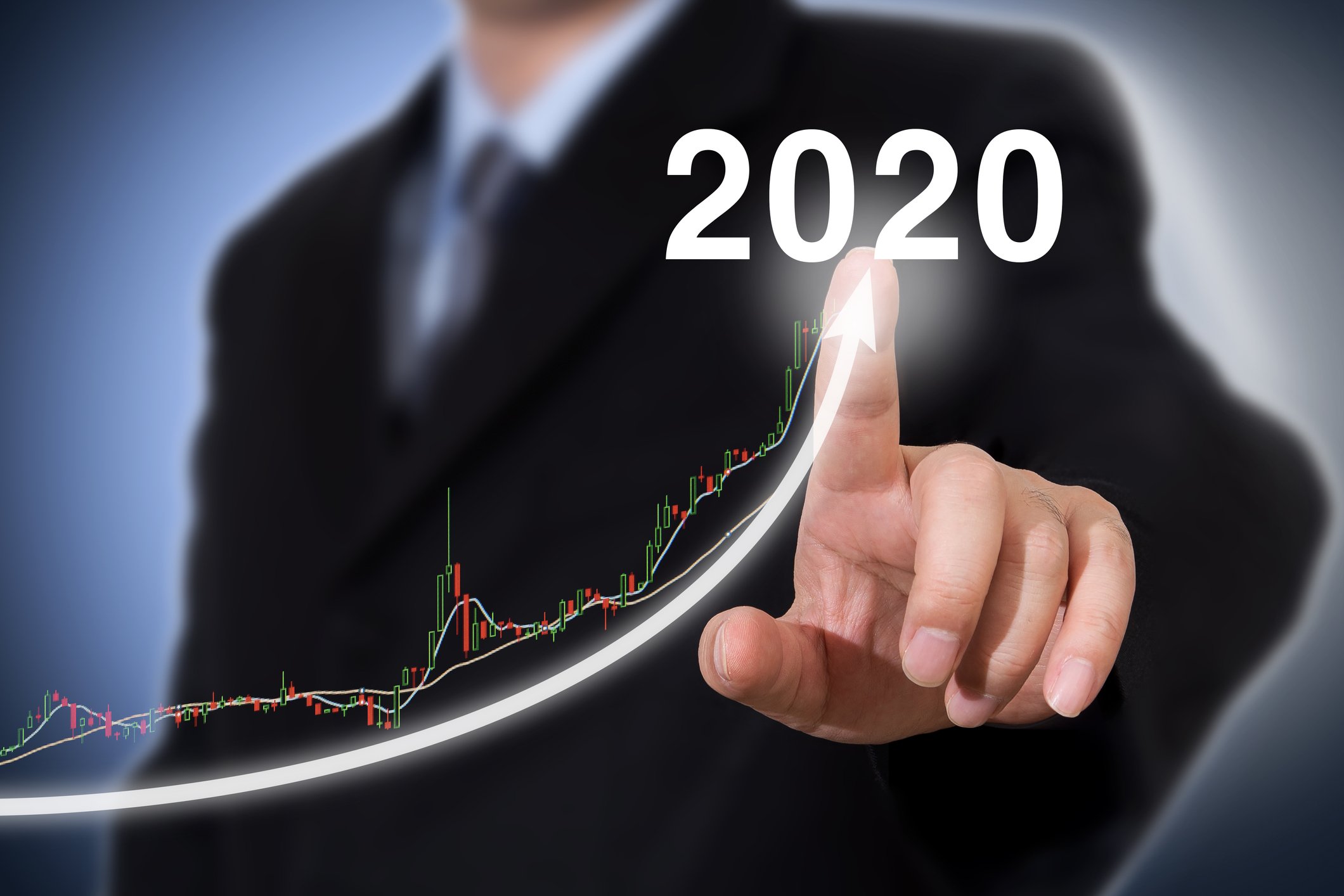 A businessmans finger tracing an upward arrow labeled 2020, with a graph showing uneven but significant growth