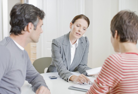 Woman sitting behind a desk showing a couple a piece of paper.