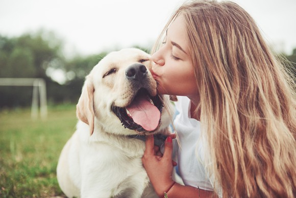 A girl kissing her dog on the face