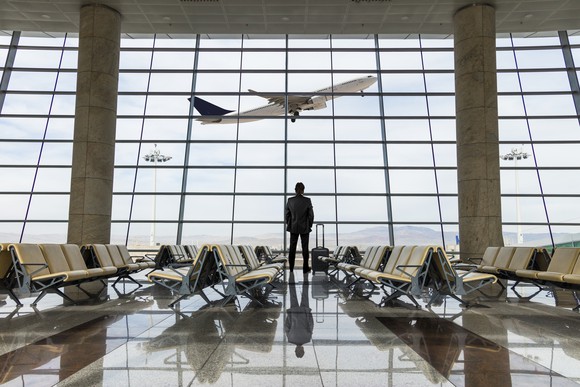 Man in an airport watching a plane take off.