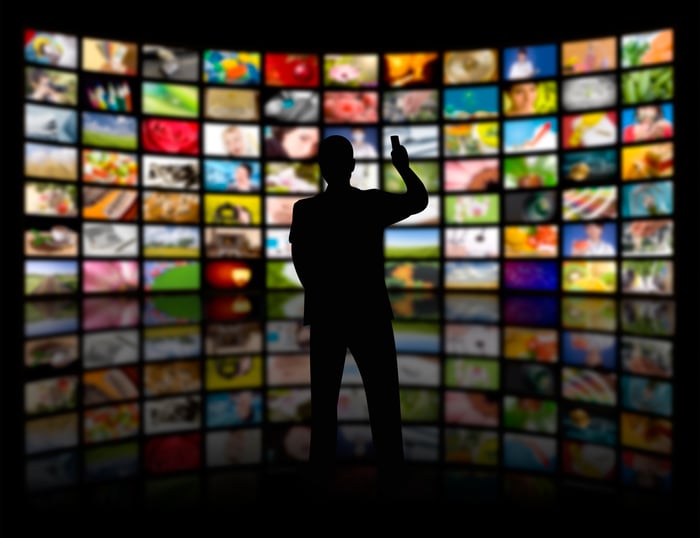 Silhouette of a man in front of dozens of TV screens.