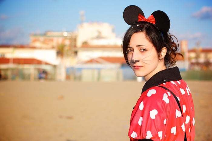 Young woman in mouse ears and makeup approaching a theme park