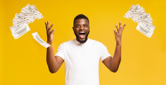 A jovial-looking young man throwing money in the air.