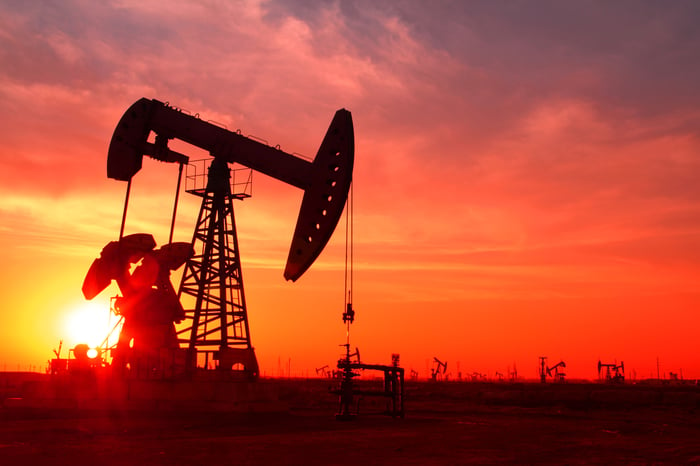 A silhouette of an oil pump in an oil field at sunset