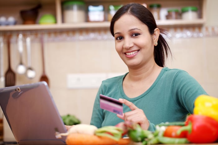 Smiling woman entering credit card into ecommerce site on laptop. 