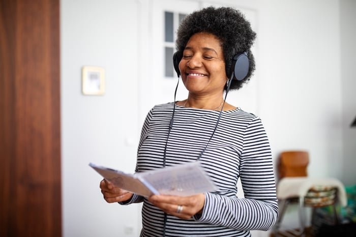 A standing woman listening to headphones with her eyes closed.