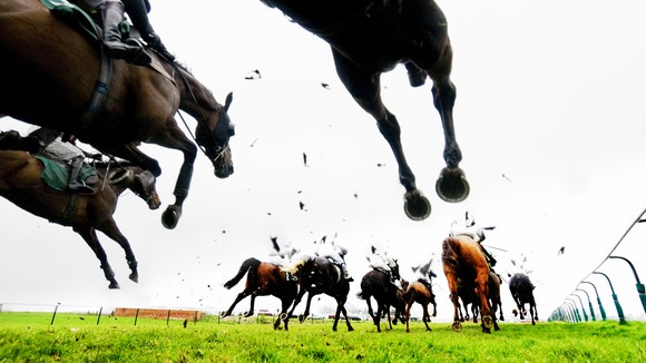 Horses' hooves kick up mud in a horse race.