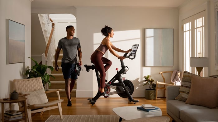 A couple taking turns on a Peloton bike.