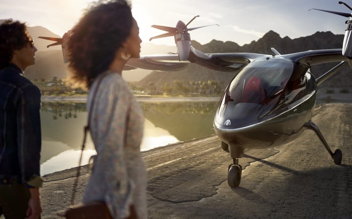 Two people next to an Archer electric aircraft.
