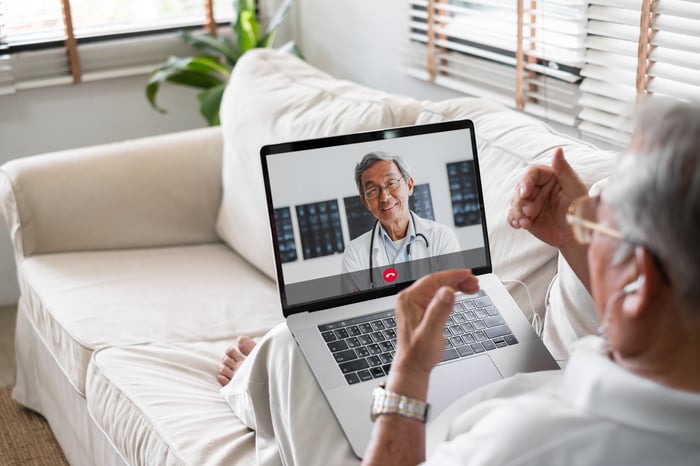 An elderly patient conducting a virtual visit with a physician using a laptop. 